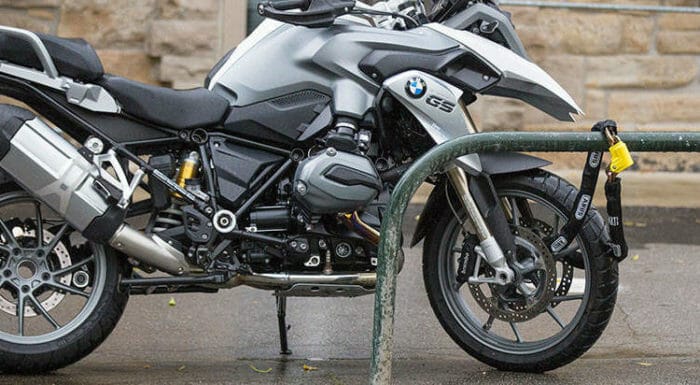 Motorcycle with security chain and padlock fixed to street furniture